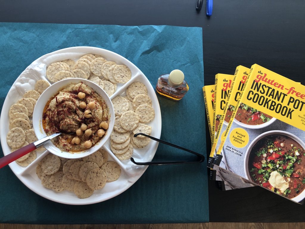 Instant Pot Hummus with crackers and a stack of Gluten Free Instant Pot Cookbooks